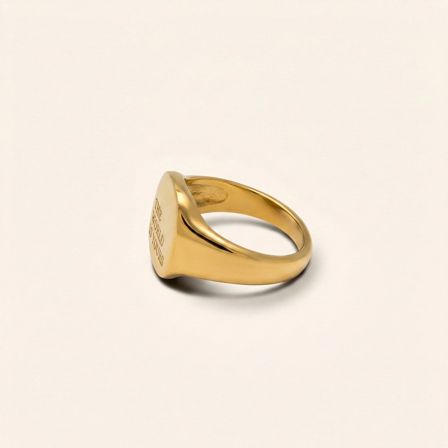 Gold ring with engraved text on a light beige background