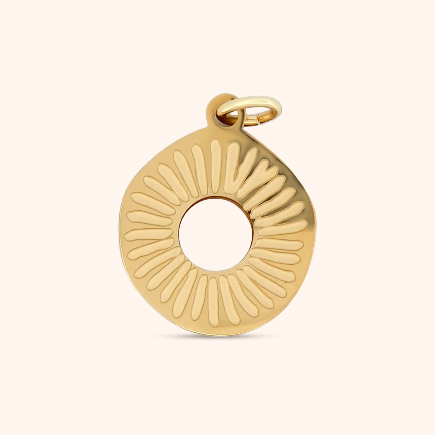 Close-up of the Desert Sun Charm, a circular gold charm featuring a sun design with a small stone at its center.