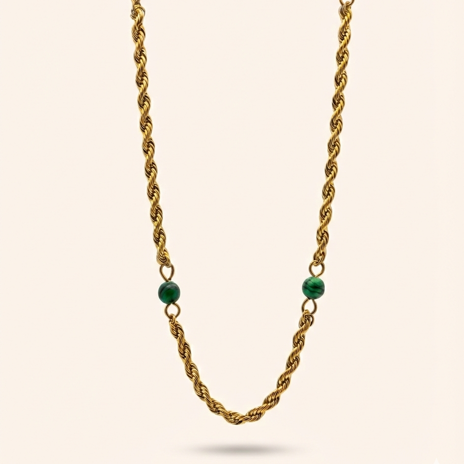 Gold chain necklace with green beads on a beige background