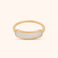 Close-up of a dainty gold ring with a slender band and a subtle strip of mother of pearl, showcasing its delicate and elegant design.
