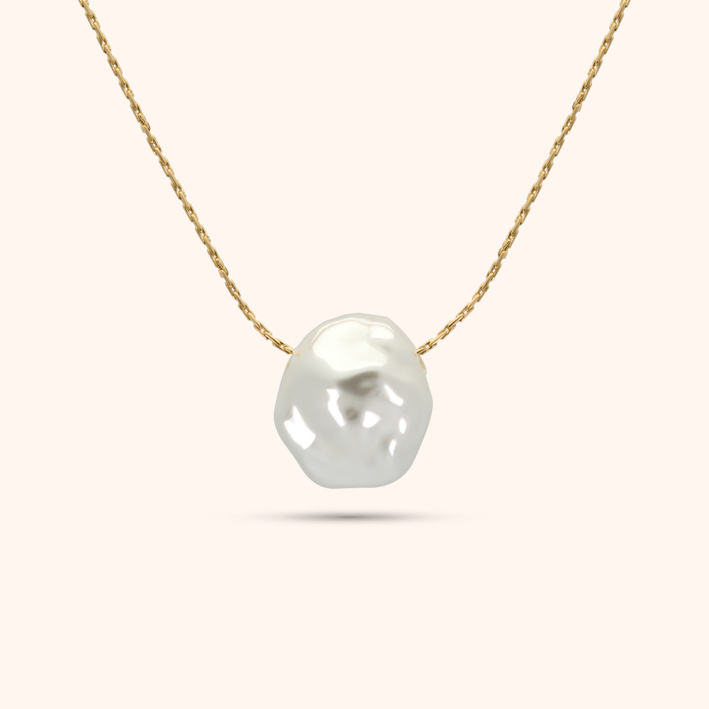 Close-up of the single baroque pearl on the PRESSIE Luster Pearl Necklace; showing its organic shape and luster on an 18k gold plated chain.