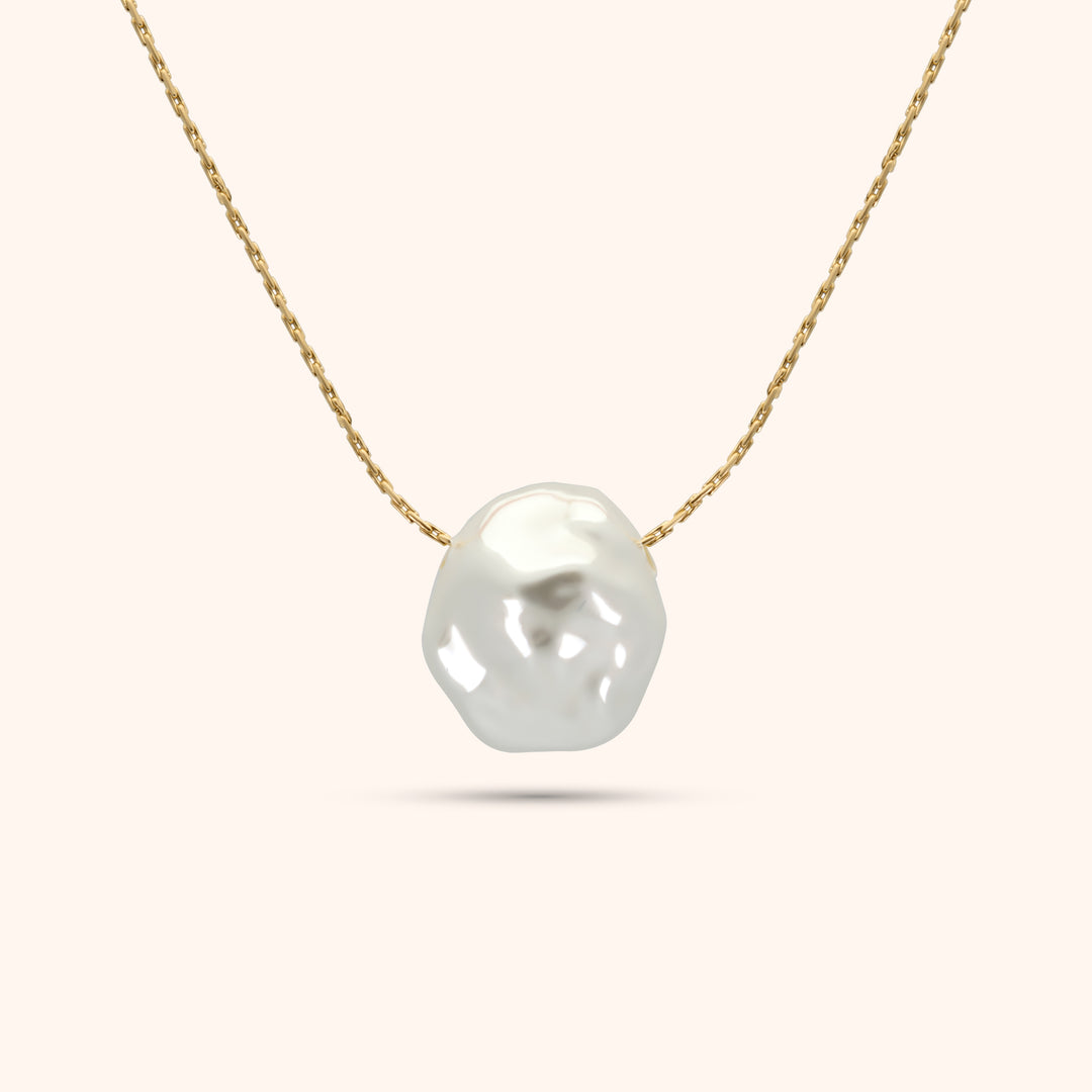 Close-up of the single baroque pearl on the PRESSIE Luster Pearl Necklace; showing its organic shape and luster on an 18k gold plated chain.