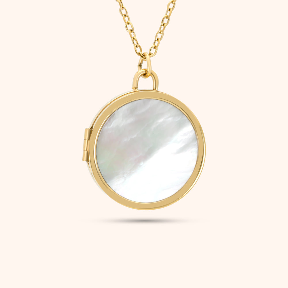 Close-up of the PRESSIE Treasured Locket; an 18k gold plated round locket with an iridescent mother-of-pearl front inlay.