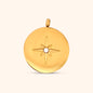 Close-up of the Stella Charm, a circular gold charm featuring a North Star design.