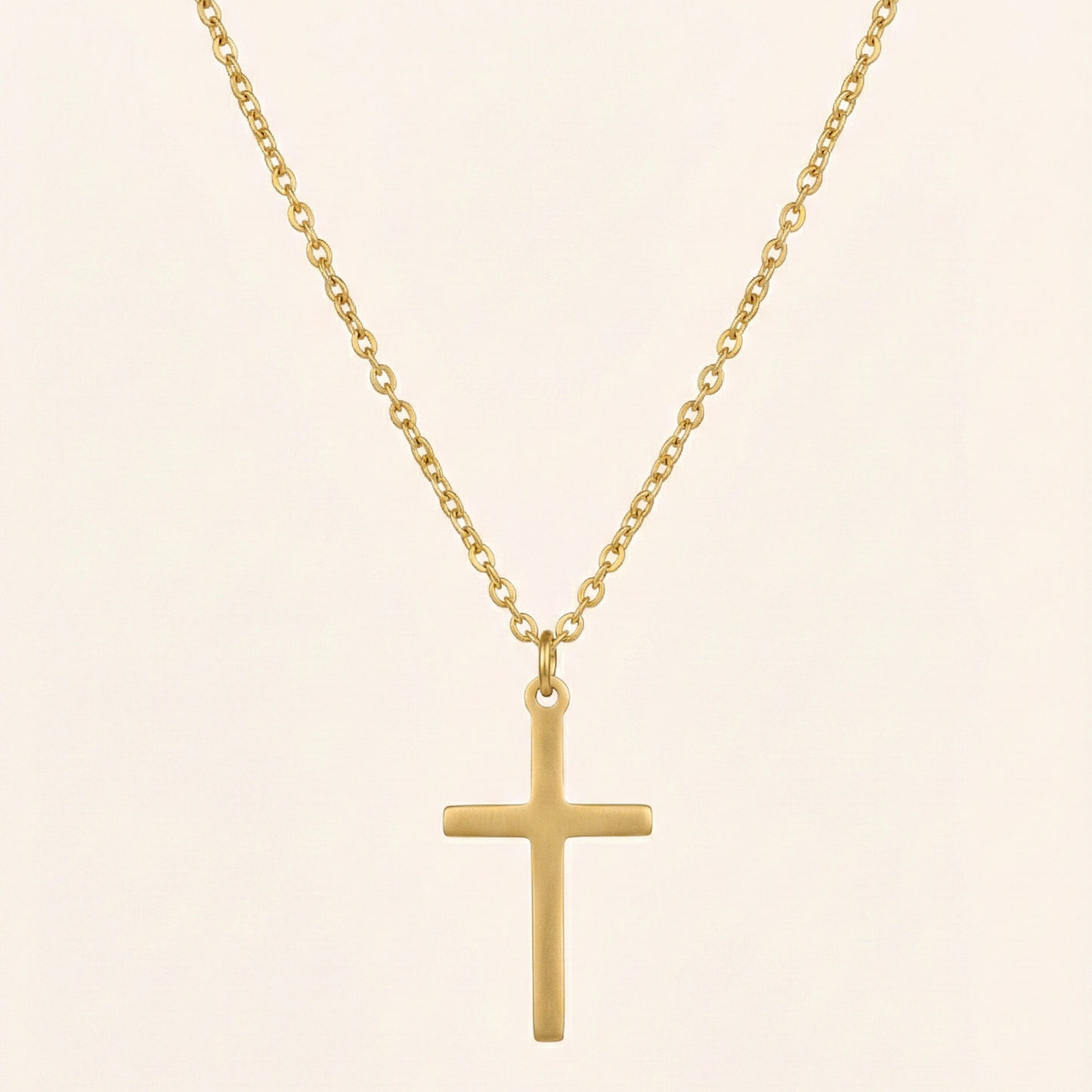 Gold cross necklace on a beige background