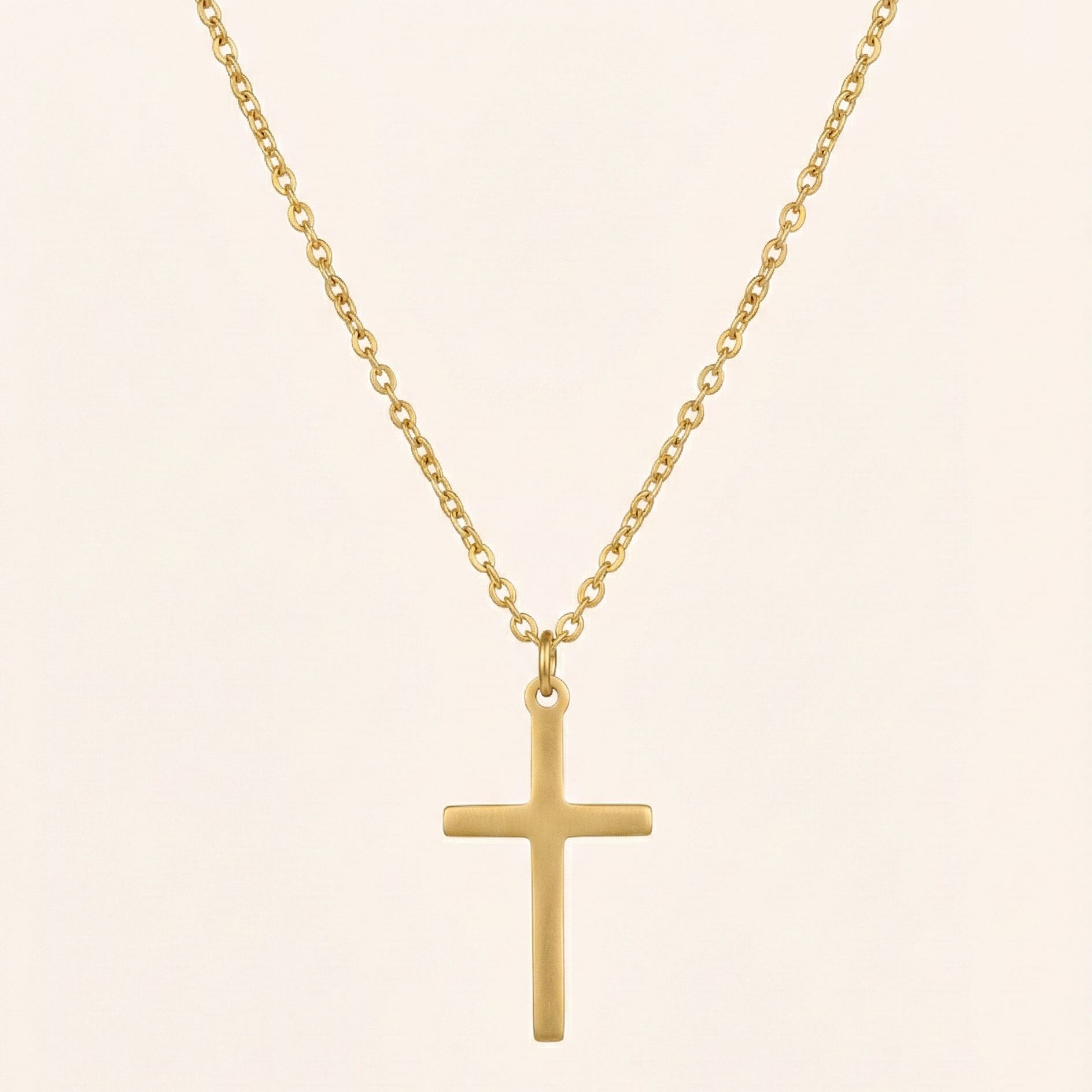 Gold cross necklace on a beige background