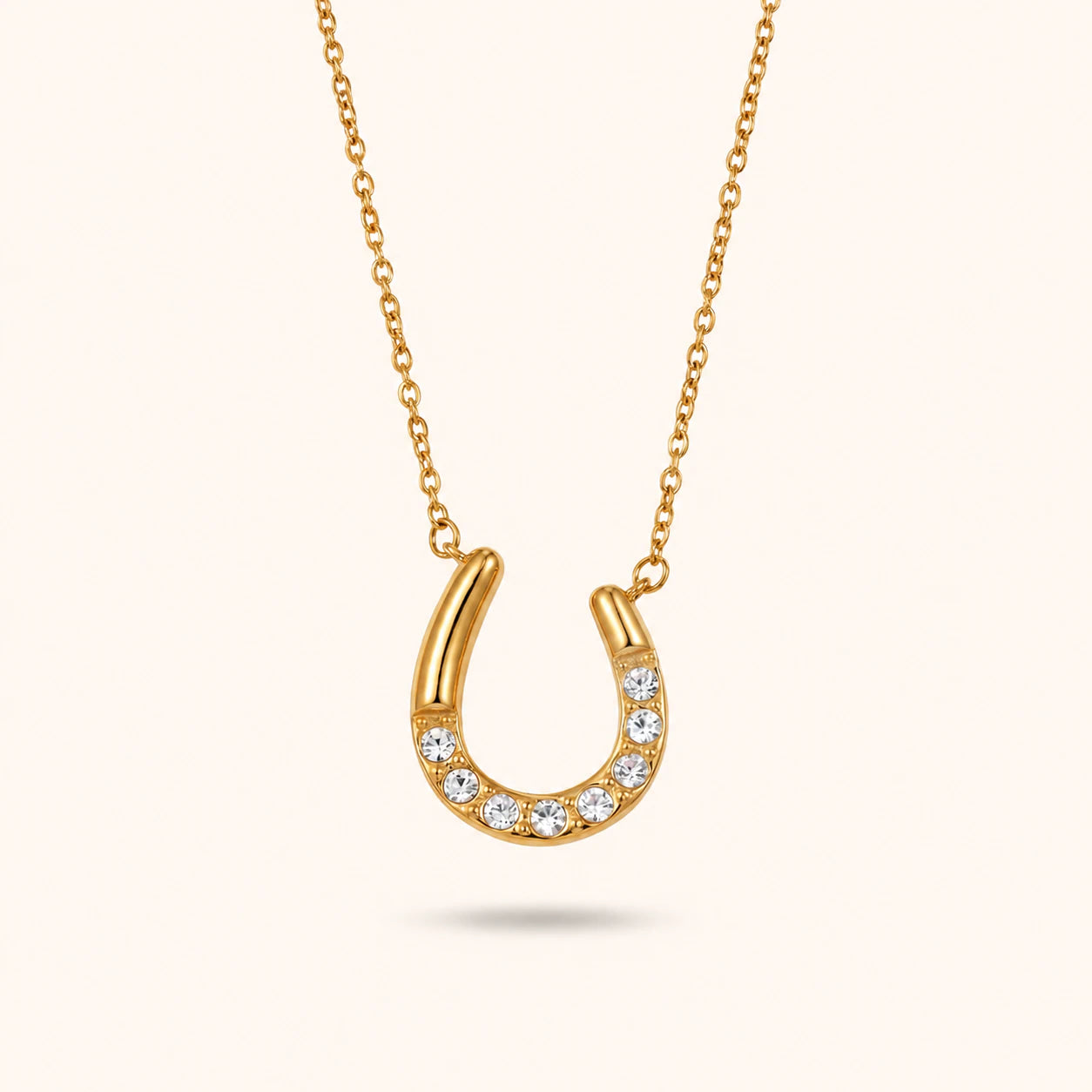 Gold horseshoe necklace with embedded diamonds on a white background