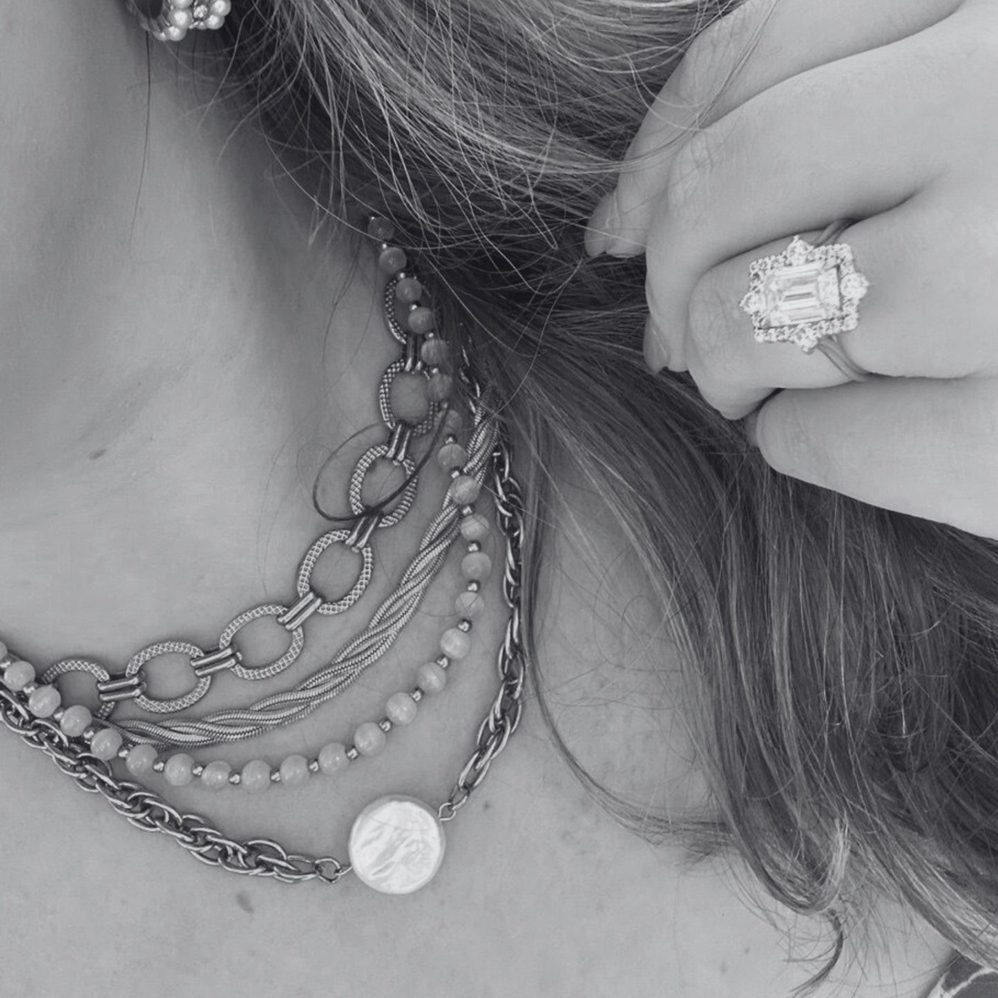 Close-up of a person wearing multiple necklaces and a ring with a diamond.