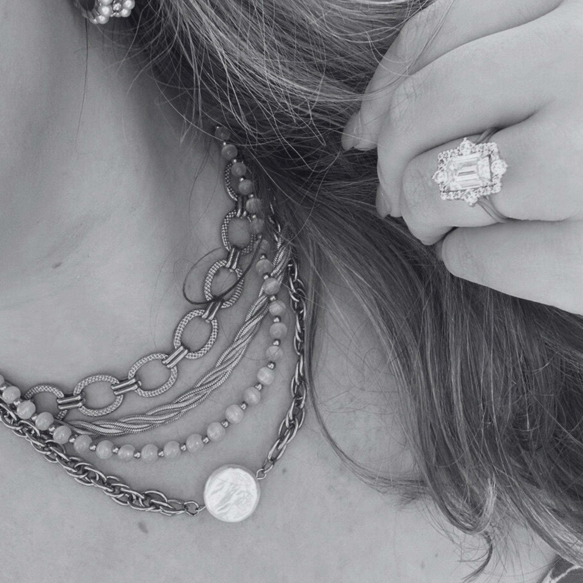 Close-up of a person wearing multiple necklaces and a ring with a diamond.