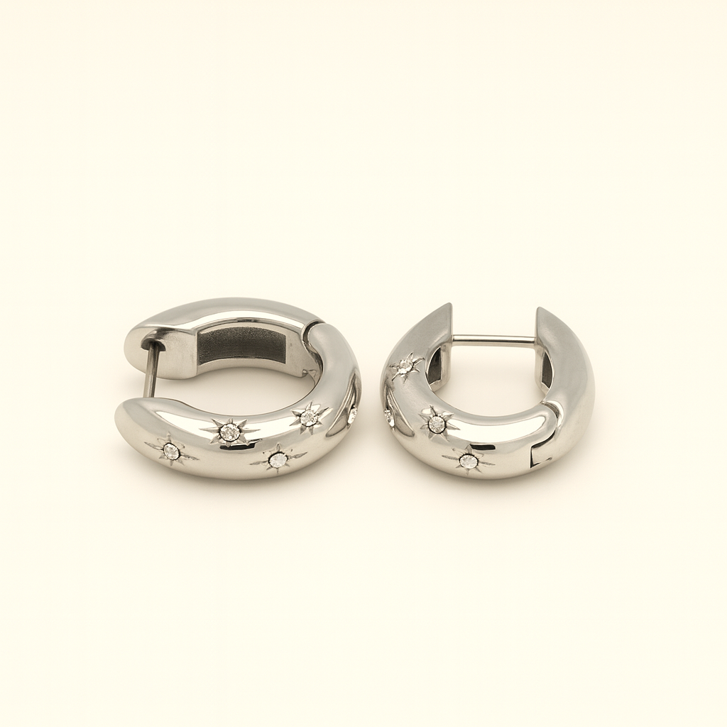 Pair of silver hoop earrings with star and gemstone details on a light beige background