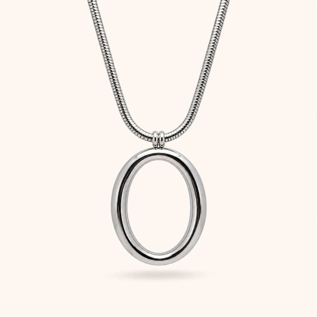 A silver snake chain necklace with a polished oval pendant, shown against a solid off-white background.