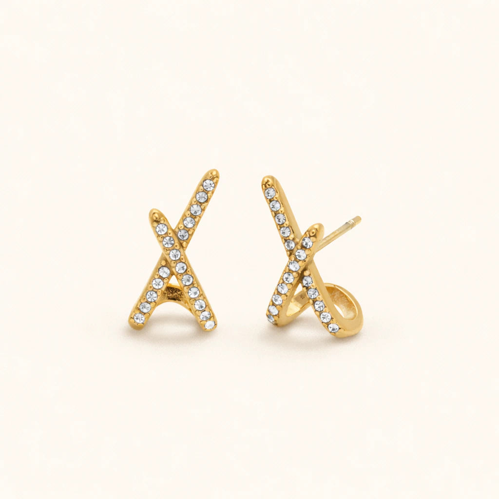 Gold 'X' shaped earrings with clear stones on a white background