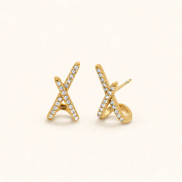 Gold 'X' shaped earrings with clear stones on a white background