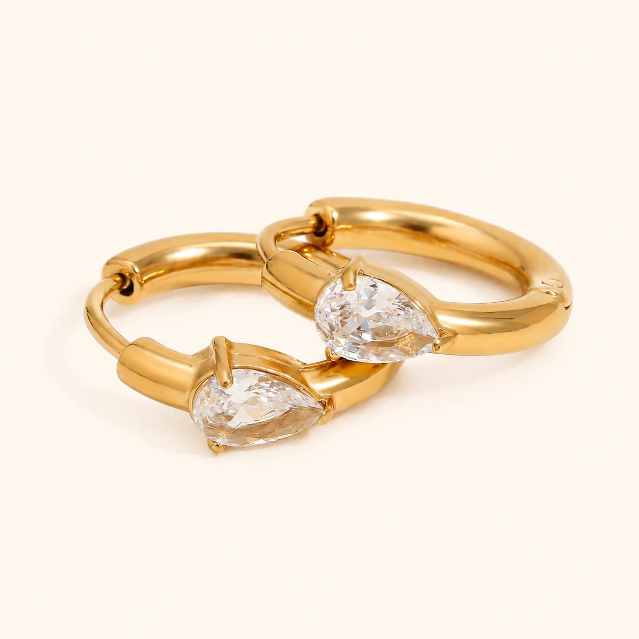 Gold ring with two pear-shaped diamonds on a beige background