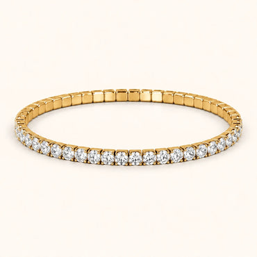 A yellow gold tennis bracelet featuring a continuous row of round-cut clear gemstones, presented on a clean, solid off-white background.