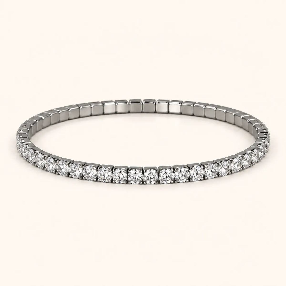 A silver-toned tennis bracelet with a continuous row of round-cut clear gemstones, displayed on a light cream background.