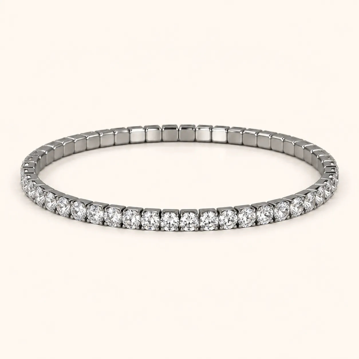 A silver-toned tennis bracelet with a continuous row of round-cut clear gemstones, displayed on a light cream background.