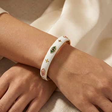 White bracelet with colorful stones on a wrist against a neutral background
