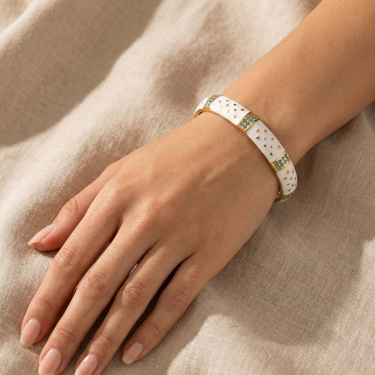 Hand wearing a bracelet on a beige fabric background