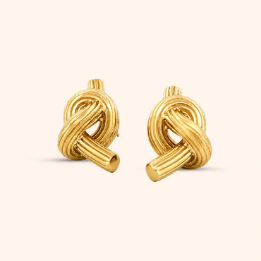 A pair of gold knot earrings with a textured design, displayed against a white background.