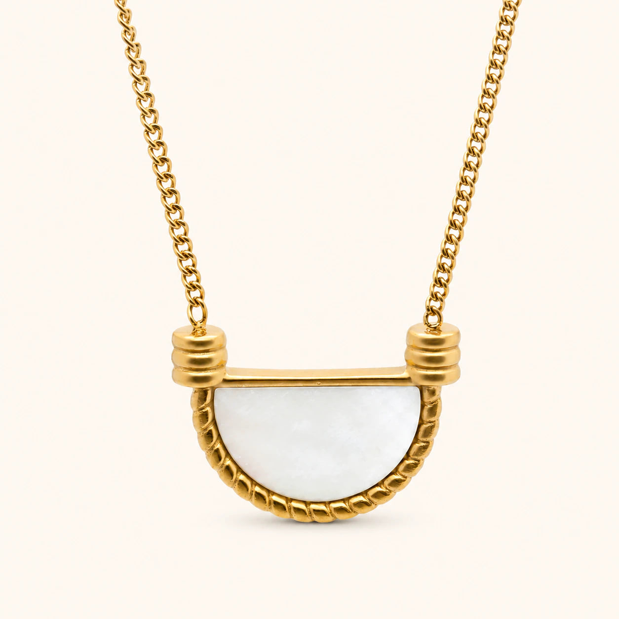 Gold necklace with a white pendant on a white background