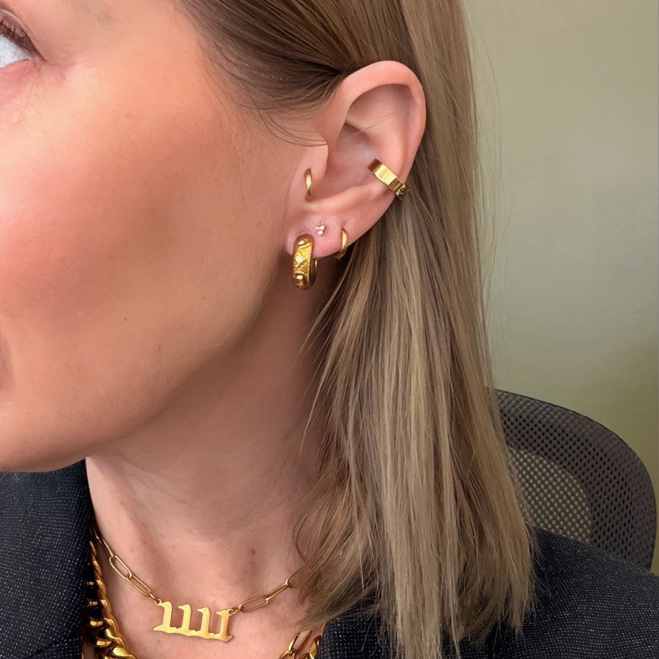 Close-up of a person wearing gold hoop earrings and necklaces.