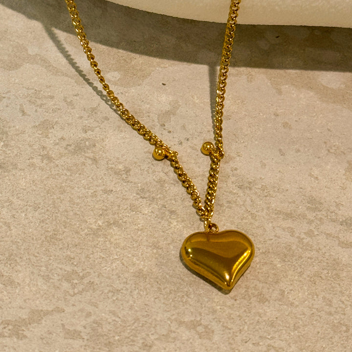 Pressie Delicate Symmetrical Heart Charm Necklace, 18K gold plated stainless steel, on model, showcasing elegant style.
