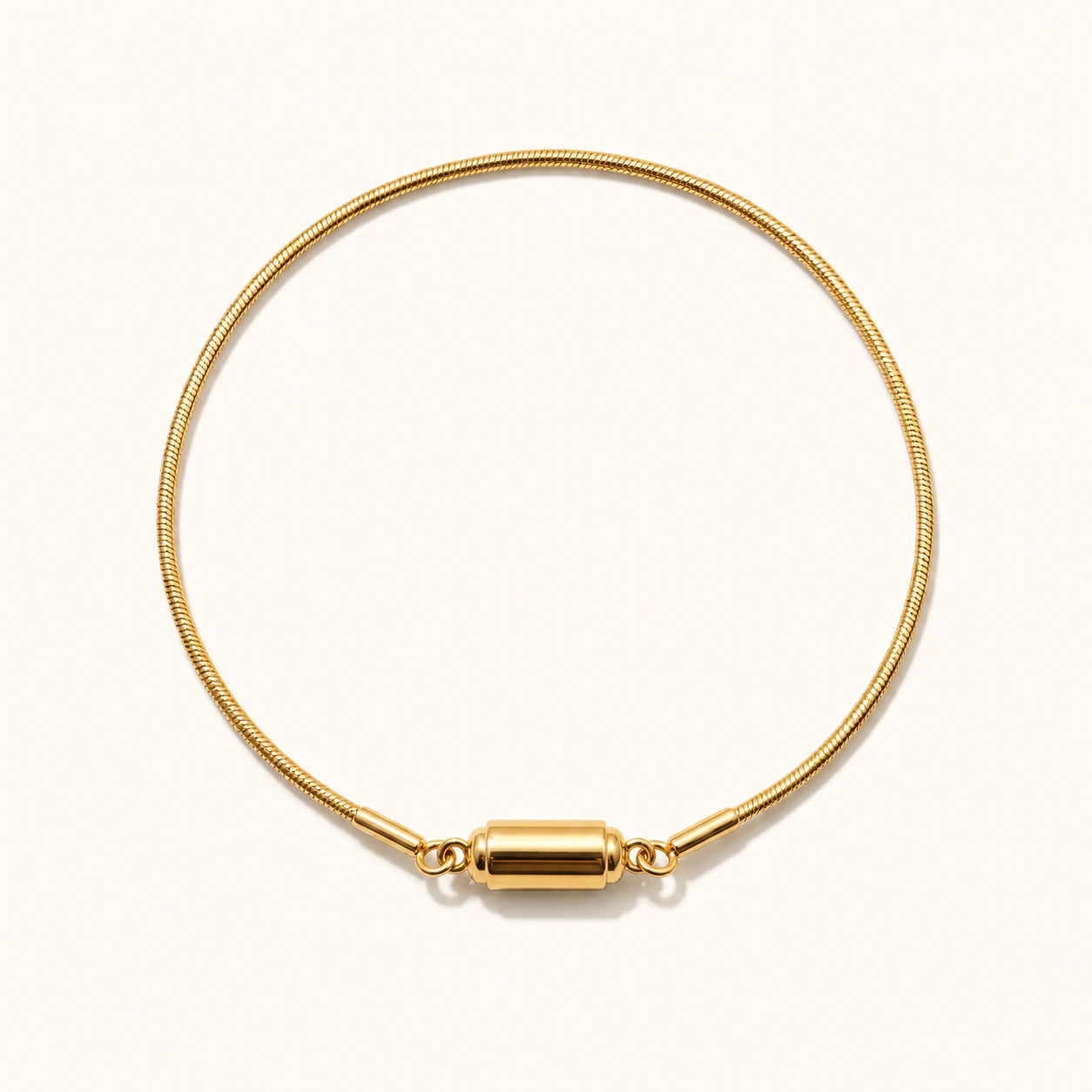 Gold bracelet with a cylindrical clasp on a white background