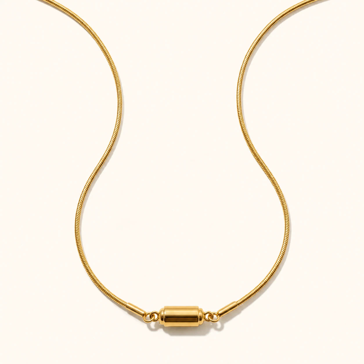Gold necklace with a cylindrical clasp on a white background