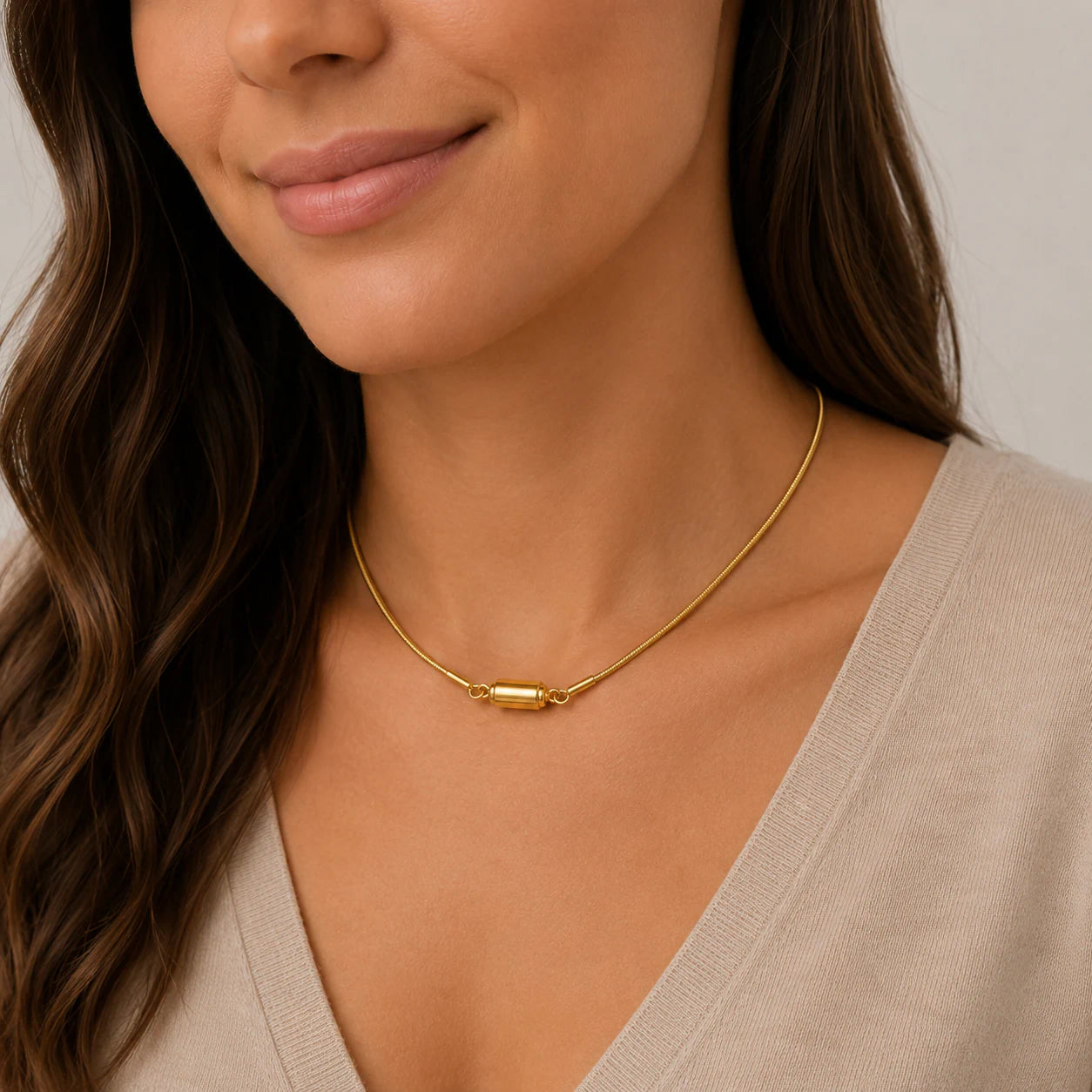 Woman wearing a gold necklace with a neutral background
