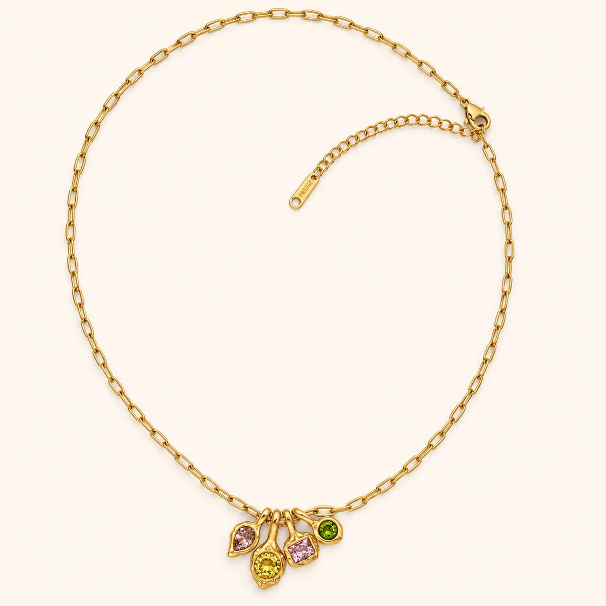 A gold chain necklace with a multi-drop pendant featuring three teardrop-shaped gemstones in pink, yellow, and green, displayed on a light cream background.