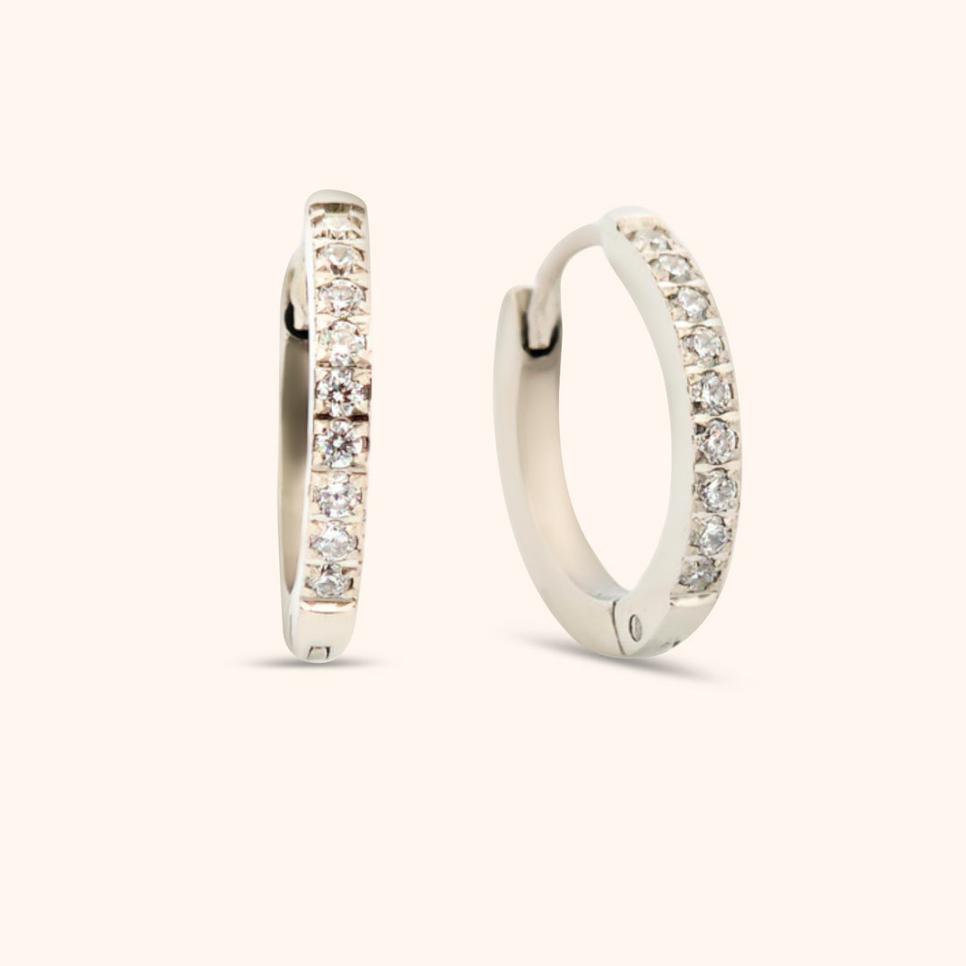 Close-up of silver huggie earring with cubic zirconia stones, waterproof and hypoallergenic