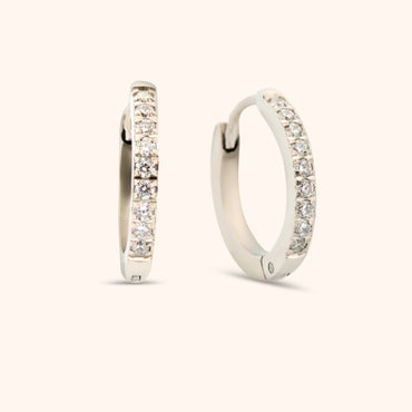Close-up of silver huggie earring with cubic zirconia stones, waterproof and hypoallergenic