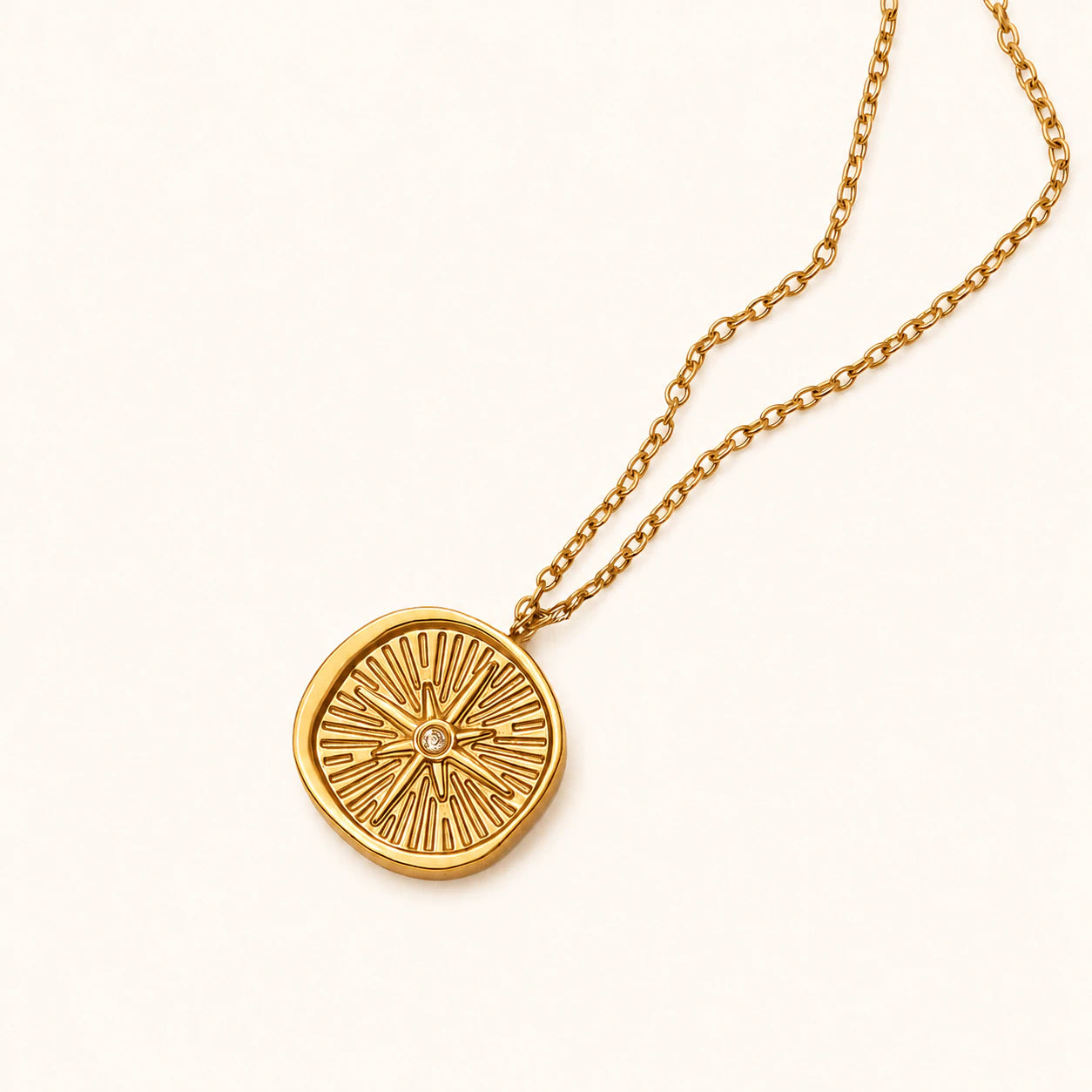 Gold necklace with a circular pendant on a white background