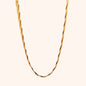 Detailed view of a gold twisted herringbone chain necklace, highlighting its smooth, fluid texture and elegant drape.