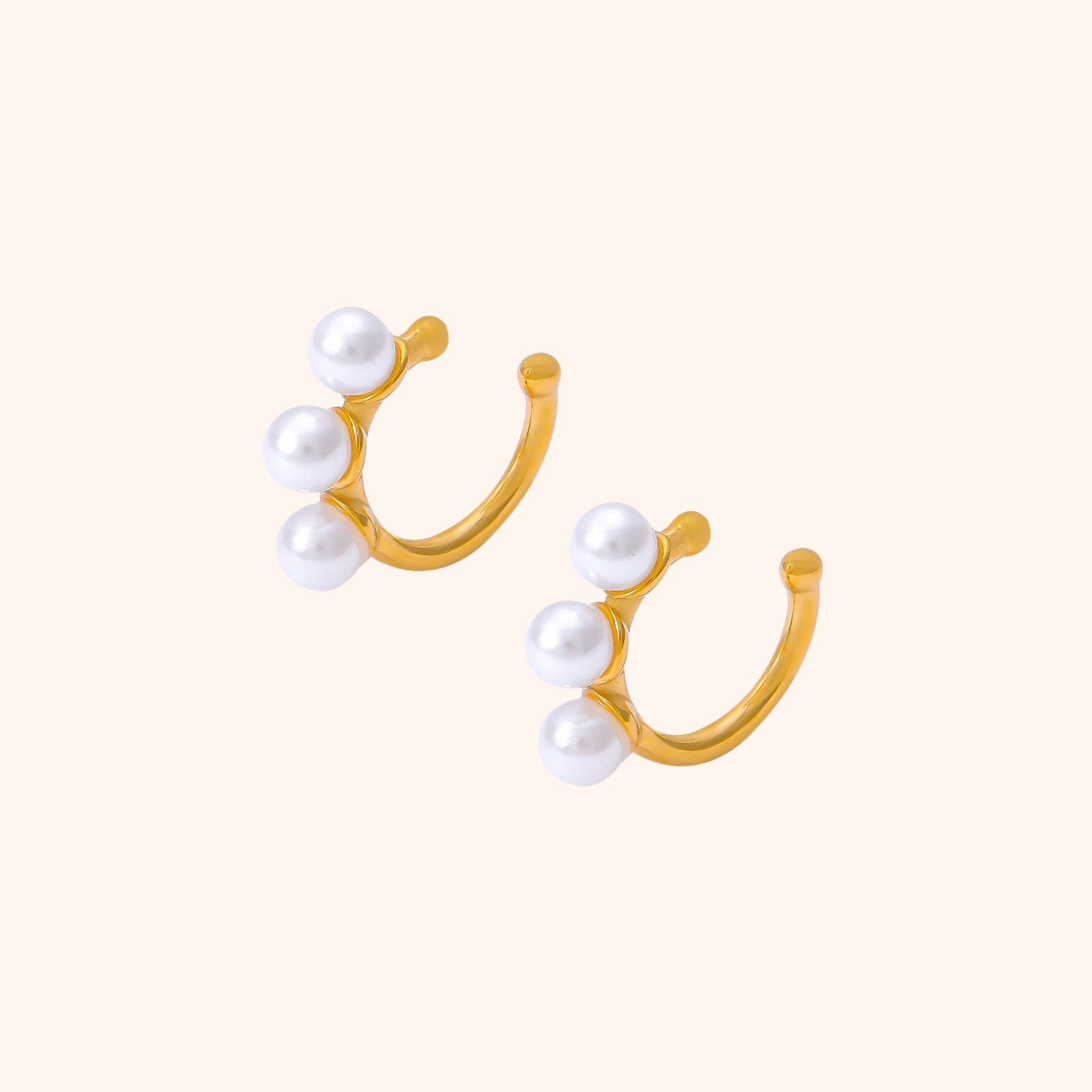 Pair of gold ear cuffs featuring three white pearls on each cuff, made of 18k gold plated stainless steel with a non-pierced design