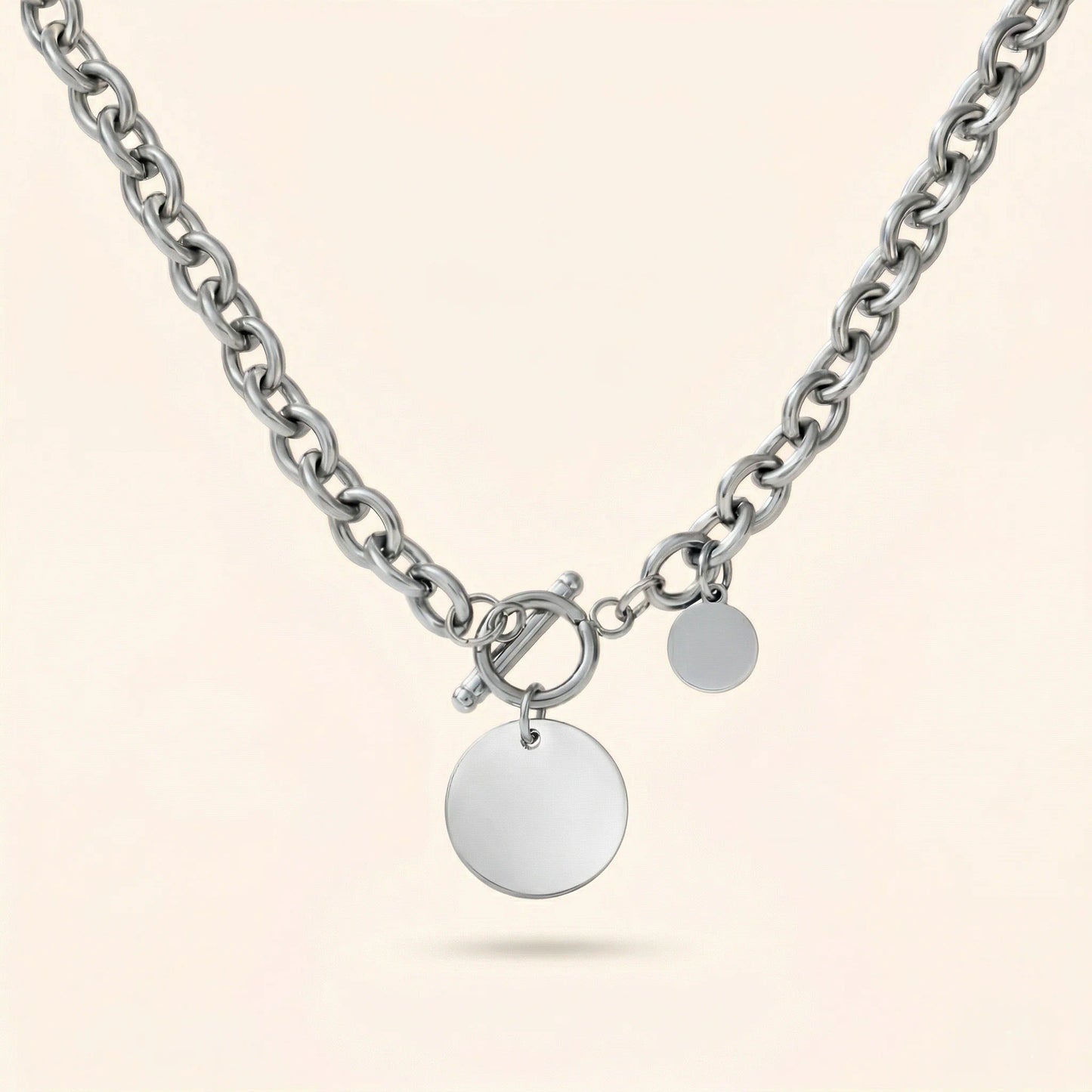 Silver chain necklace with round pendants on a light beige background