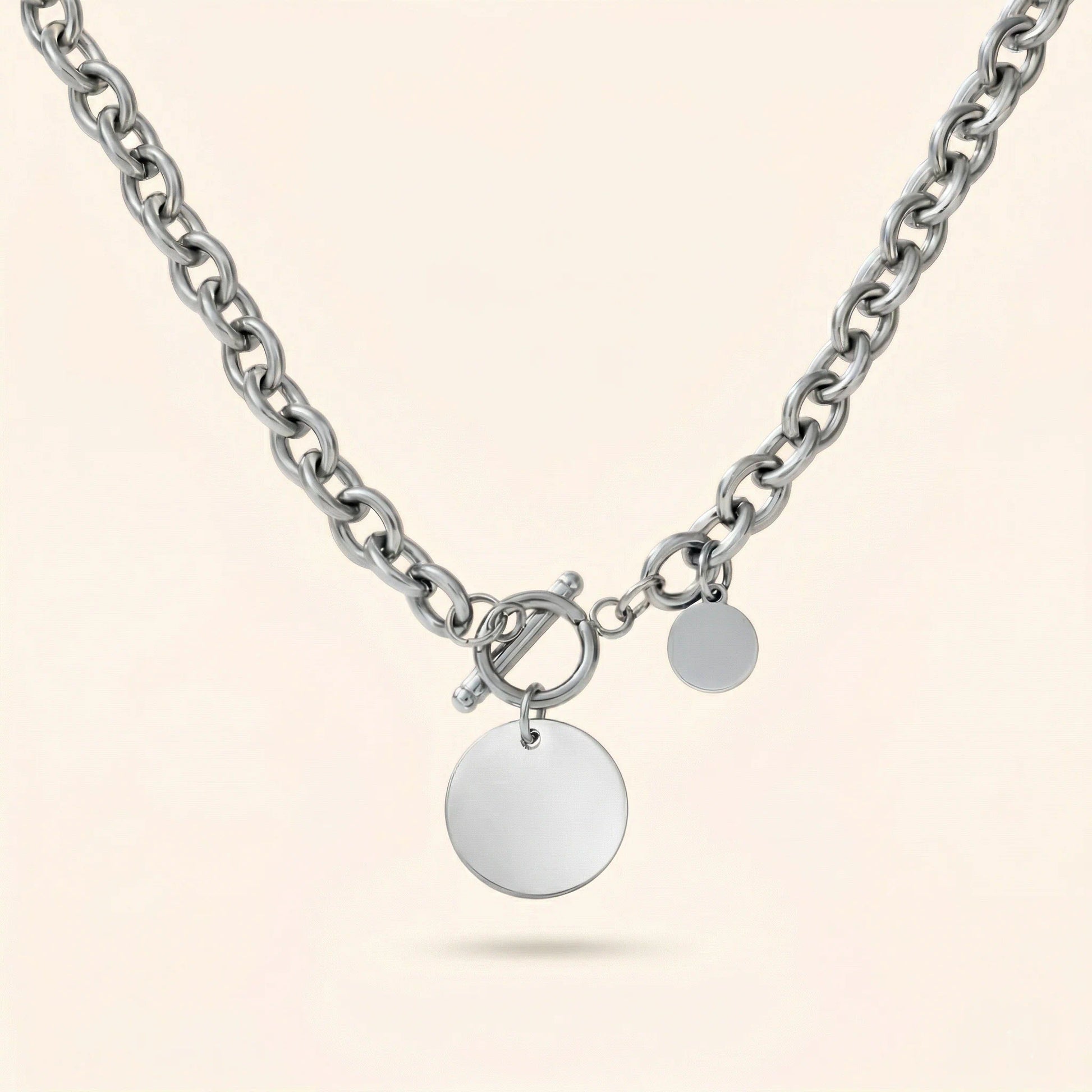 Silver chain necklace with round pendants on a light beige background