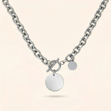 Silver chain necklace with round pendants on a light beige background
