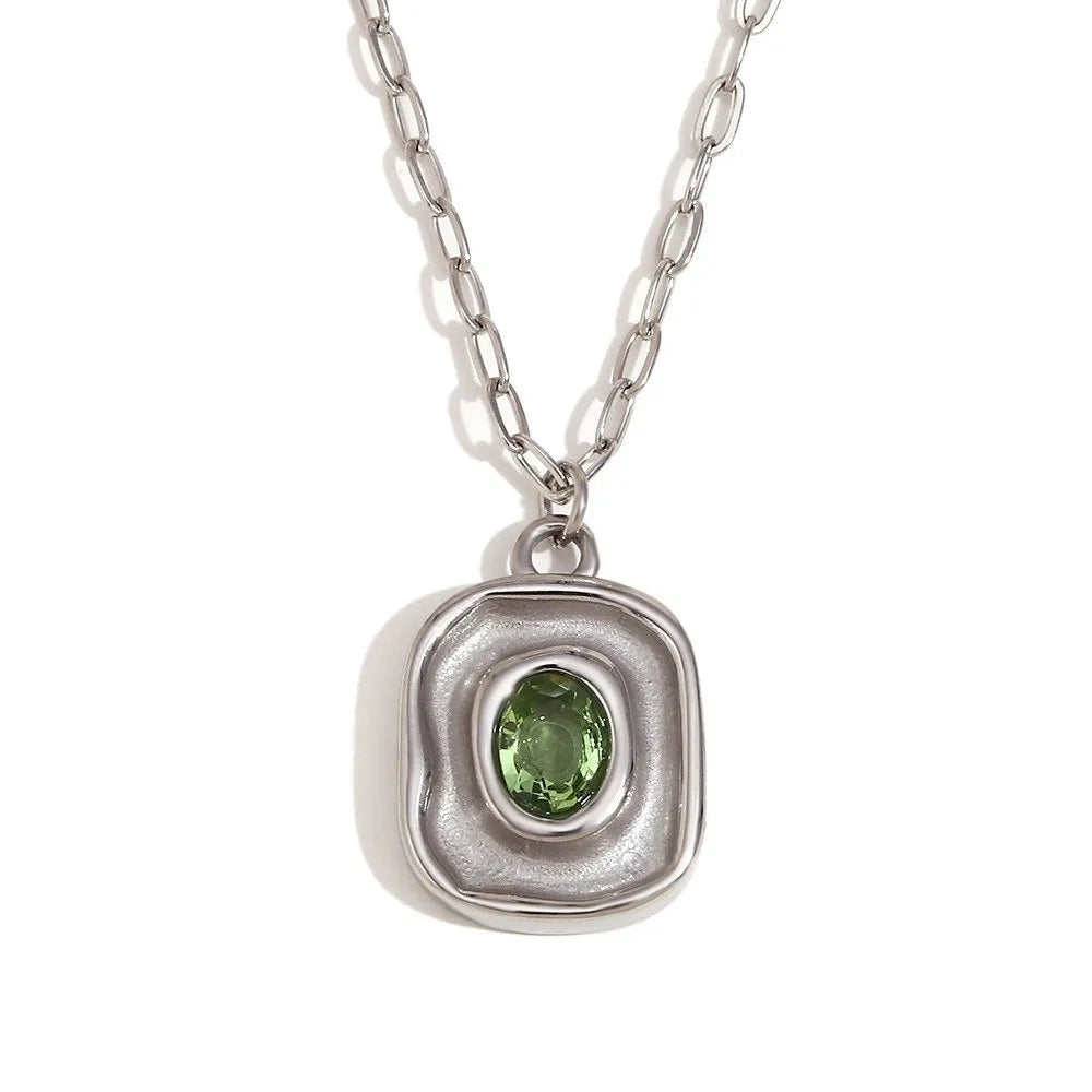 Silver pendant with a green gemstone on a white background