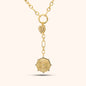 PRESSIE Radiant Heart Lariat necklace in 18k gold plate; features mixed paperclip chain, a central circular connector with a pavé heart charm, and a lariat drop ending in a sunburst medallion with clear stone accents.