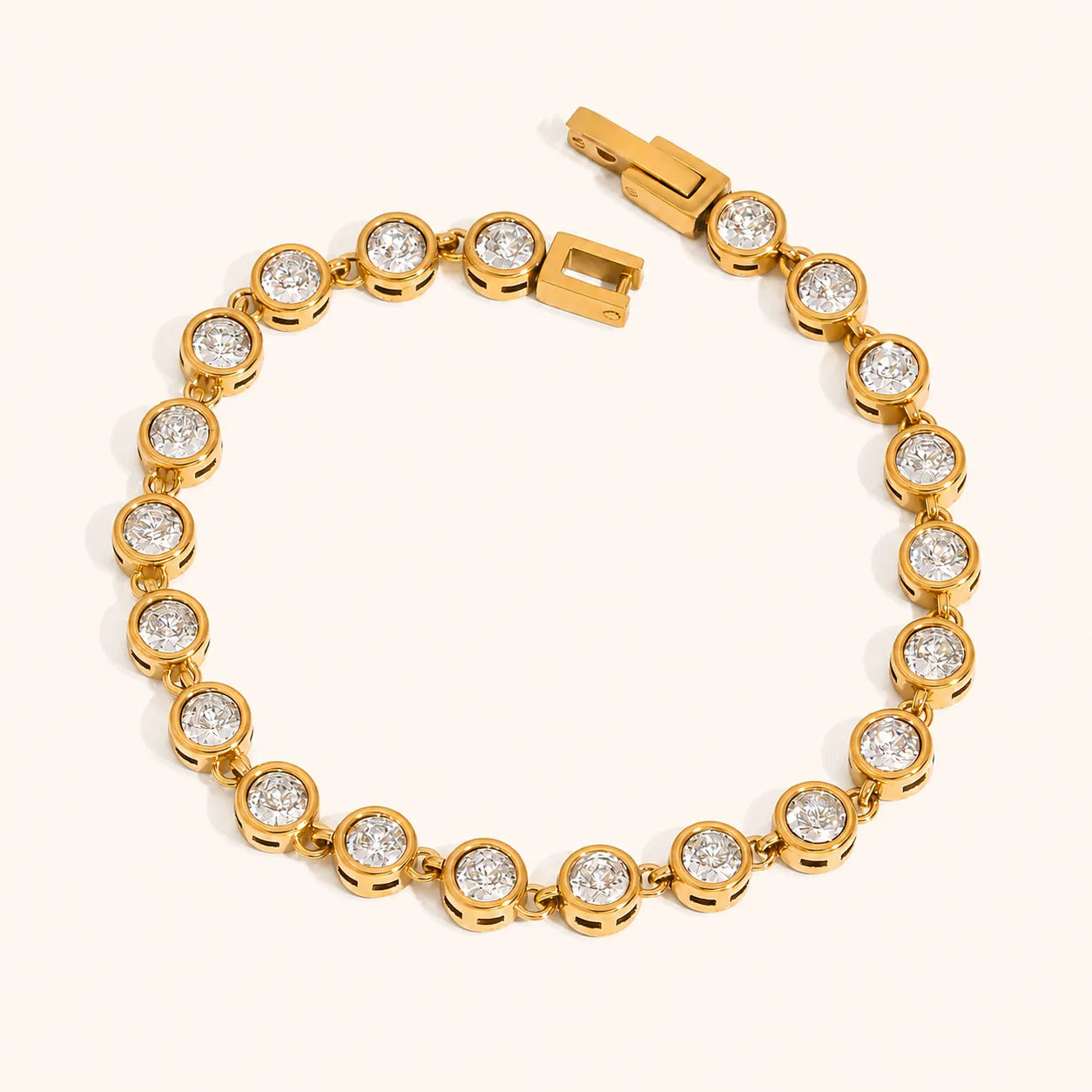 A yellow gold tennis bracelet featuring round bezel-set clear gemstones, arranged in a circular shape on a light cream background.