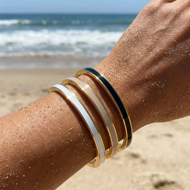 Close-up of a person's wrist with multiple bracelets on a beach.