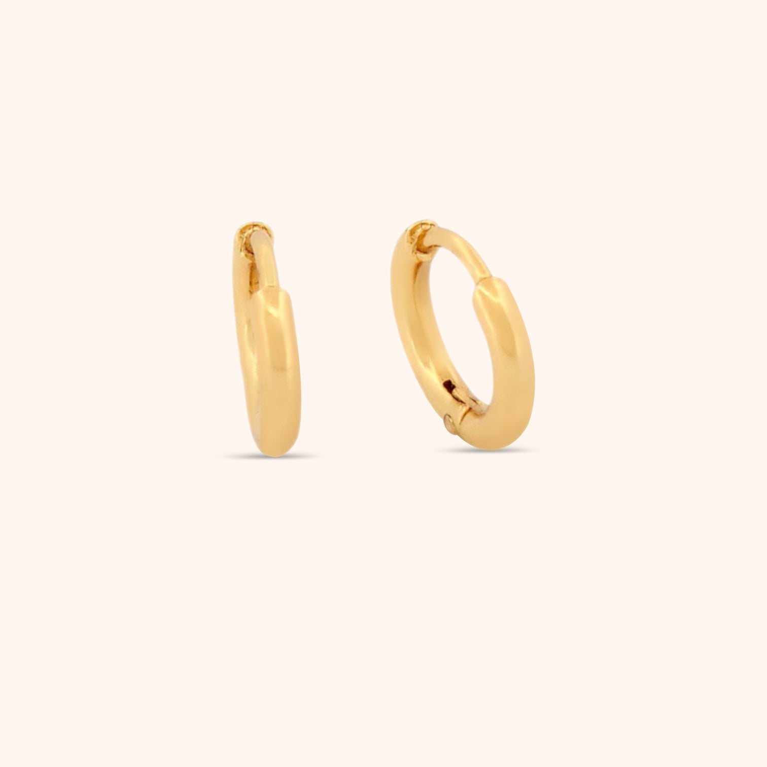 Close-up of a dainty gold huggie earring, showcasing its delicate design and subtle shine.
