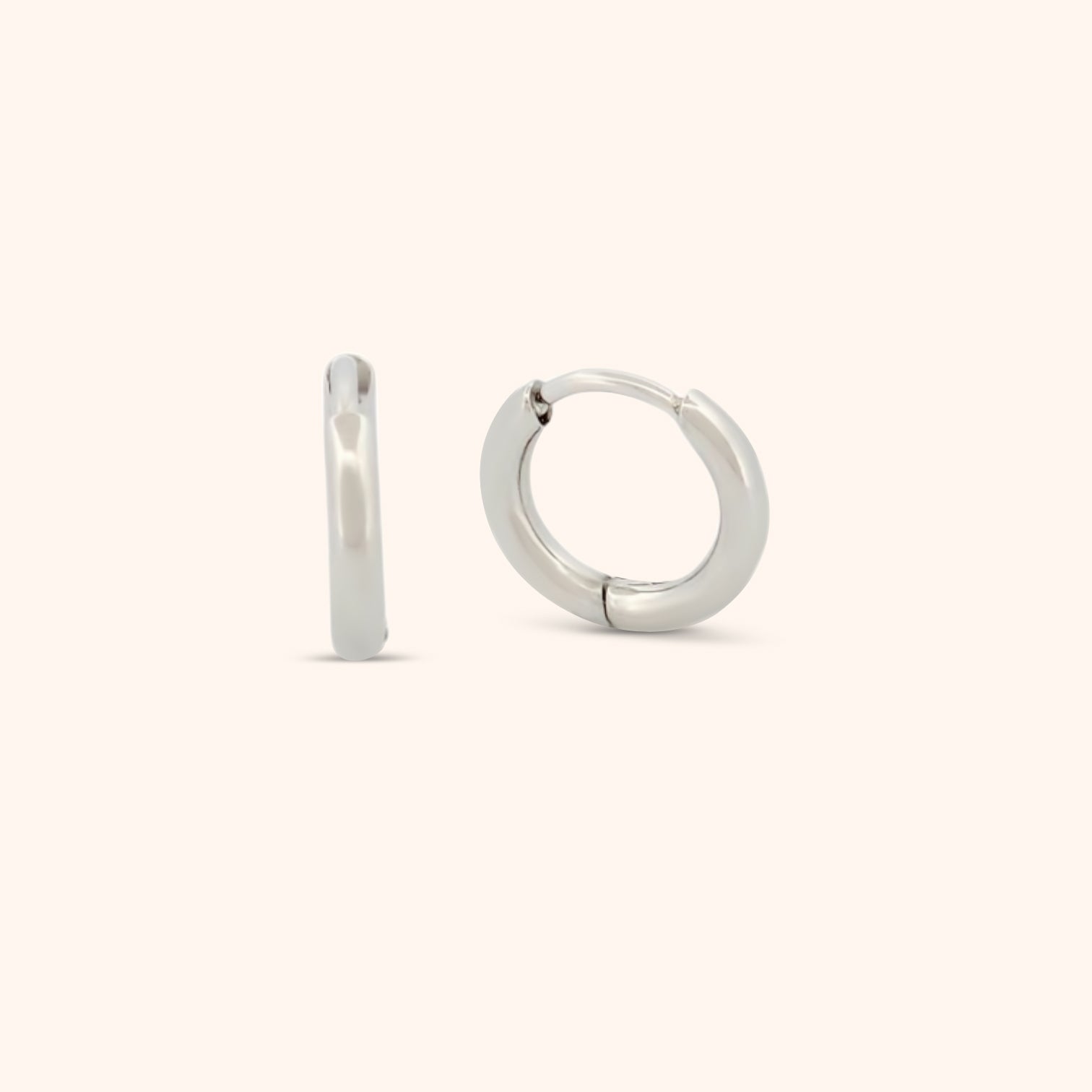 Detailed view of a dainty silver huggie earring, highlighting its minimalist and elegant style.

