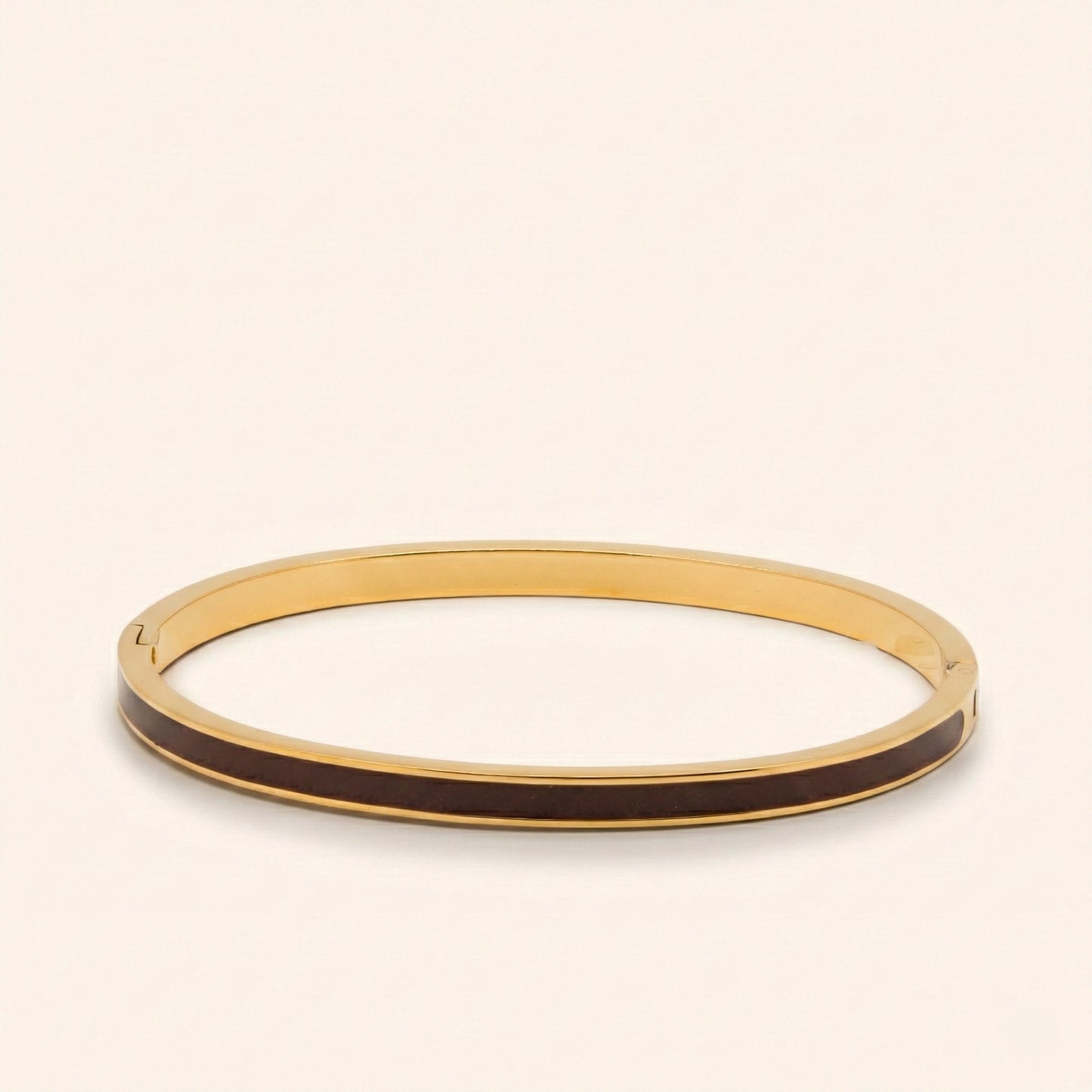 Gold bangle with black interior on a beige background
