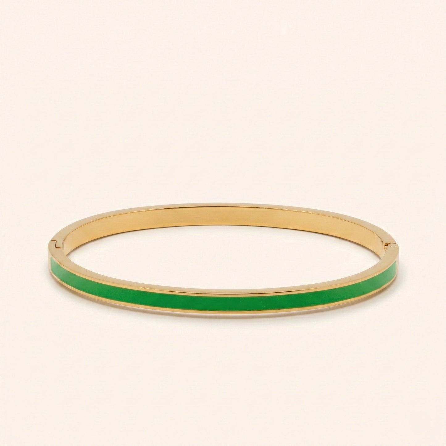 Gold bangle with green interior on a beige background
