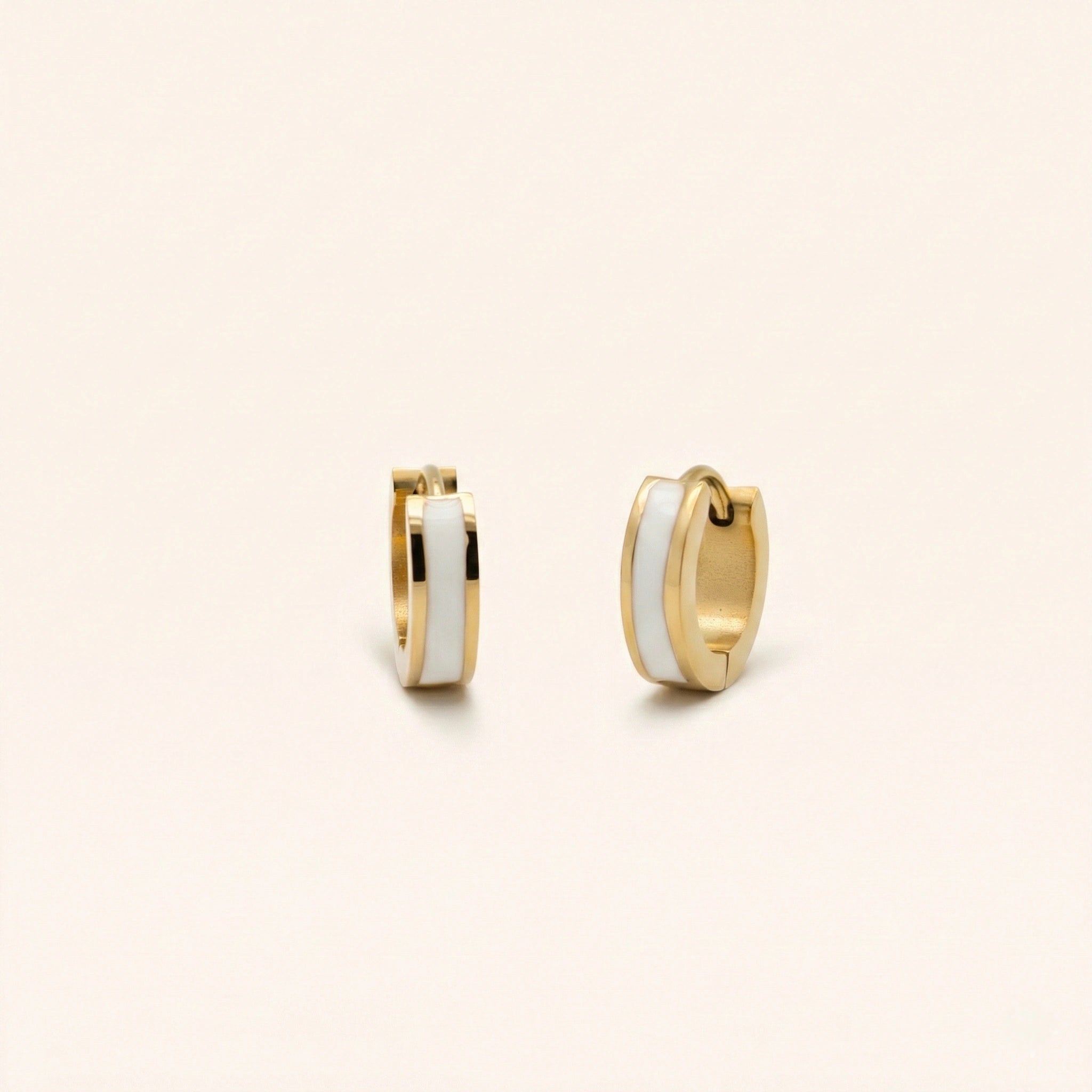 Gold hoop earrings with white centers on a beige background