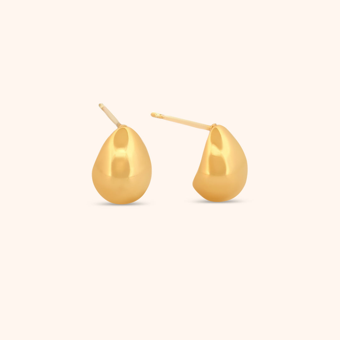 Close-up of gold teardrop earrings, showcasing their smooth, polished surface and modern, sculptural design.
