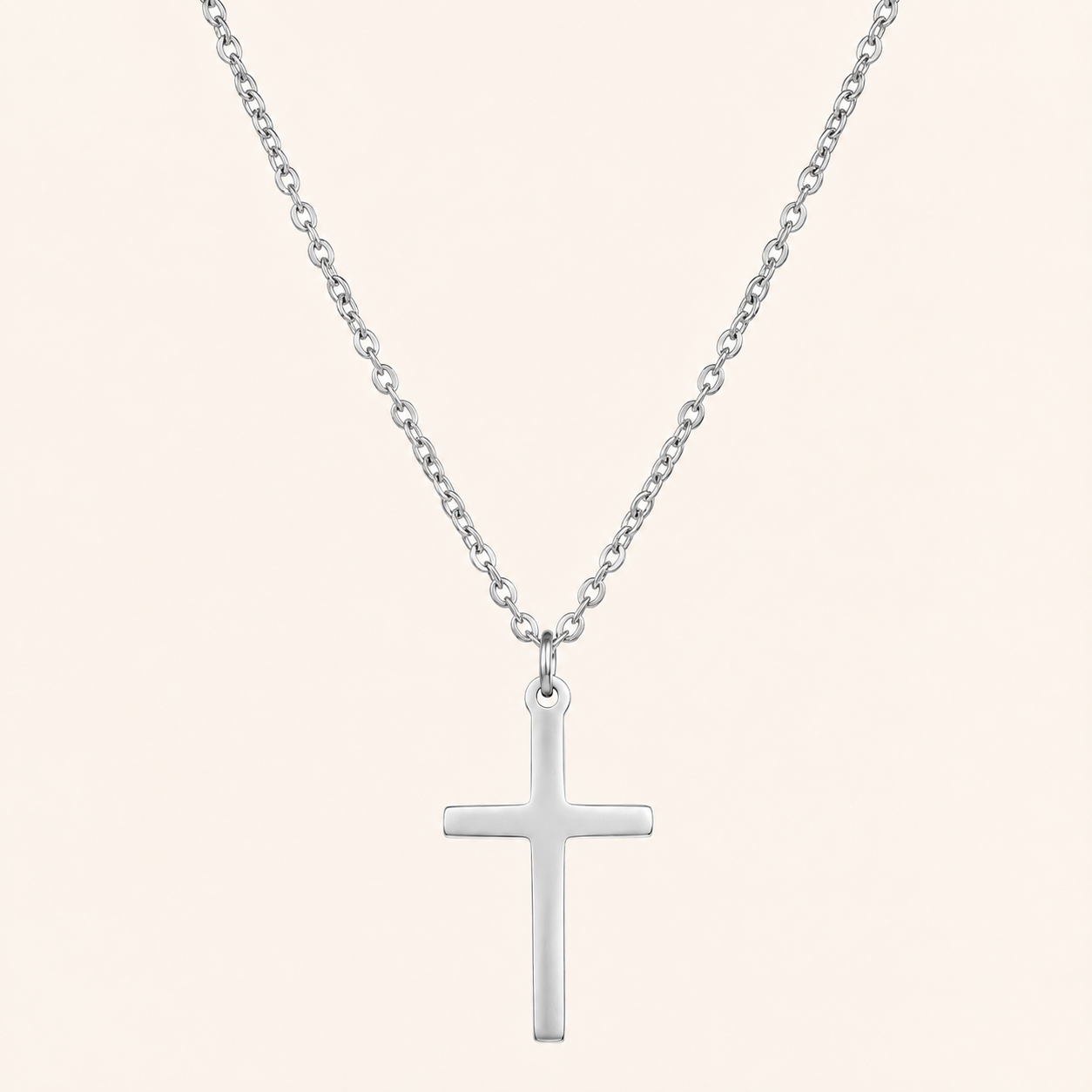 Silver cross necklace on a light beige background